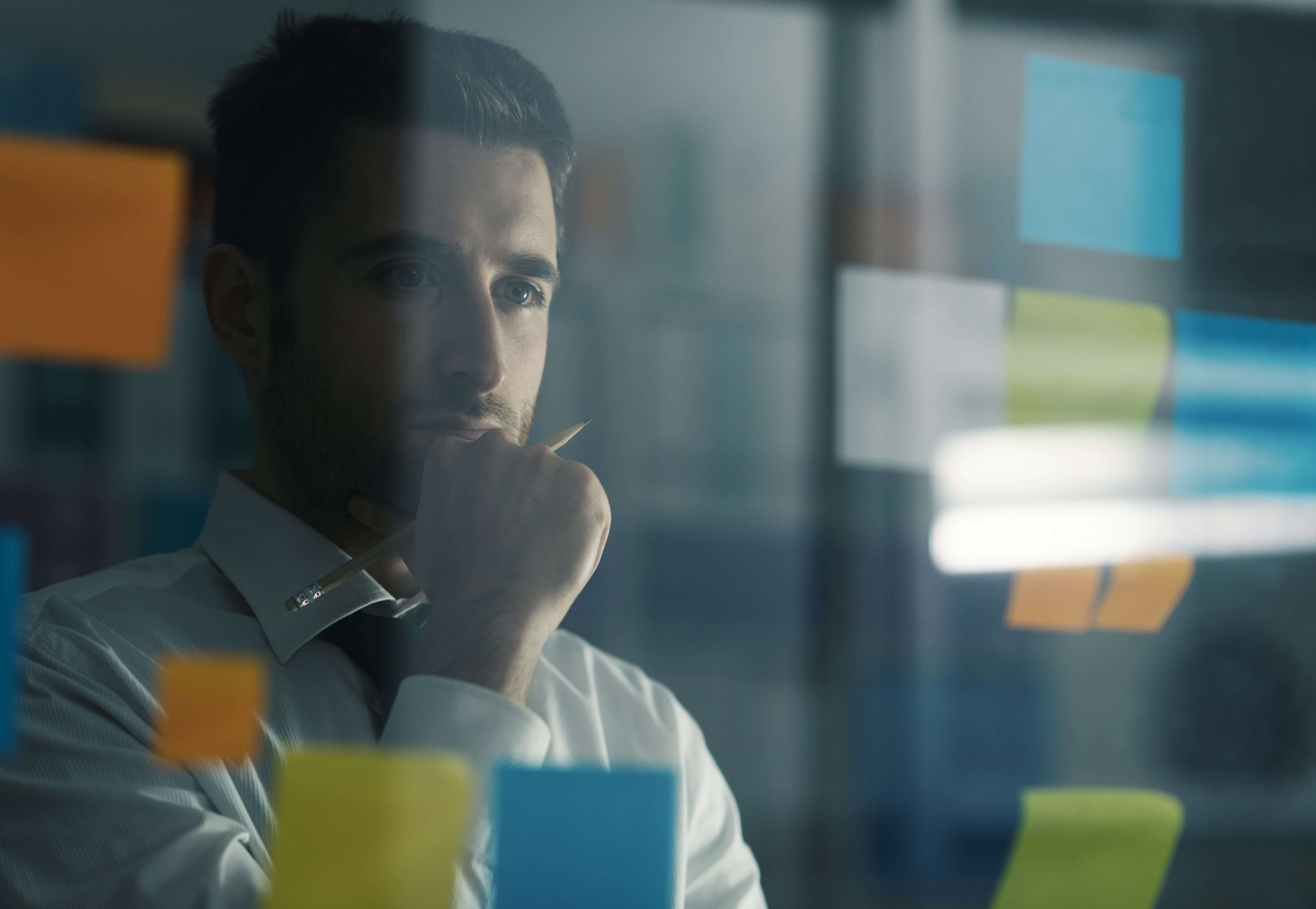 Man looking at multiple post it notes debating best billing style.