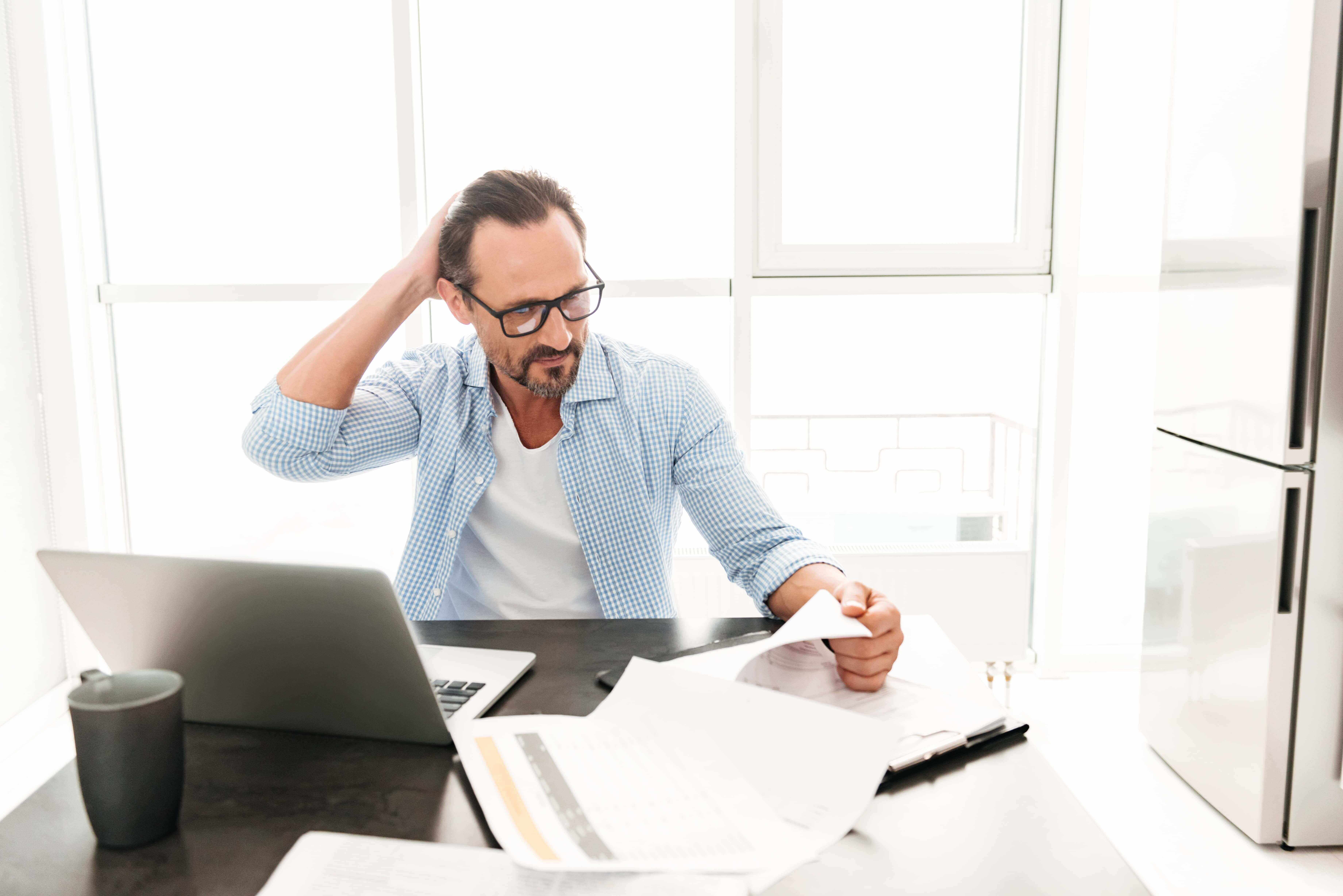 Man frustrated looking over his 2019 tax documents in preparation for the 2020 filing season.