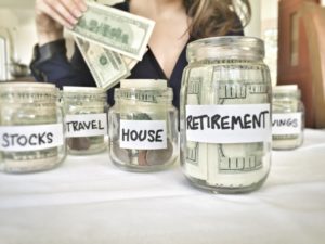 mason jars filled with money with labels like retirement, house, travel